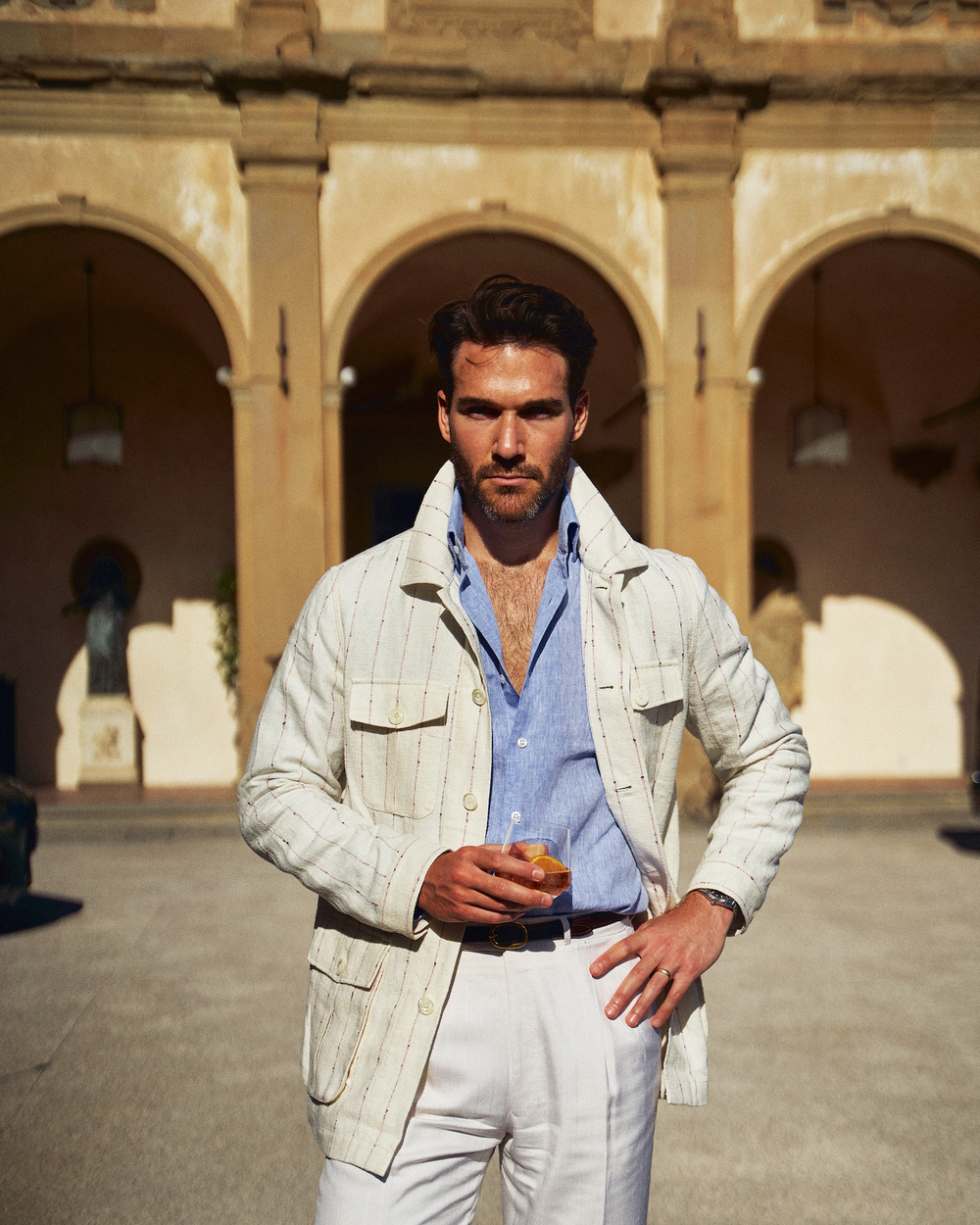 A young gentleman is standing in a stylish summer safari jacket